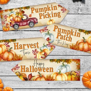 May include: Four printable signs with autumn and Halloween themes. The signs feature pumpkins, autumn leaves, and a red truck. The signs read "Pumpkin Picking", "Pumpkin Patch This Way", "Harvest Time", and "Happy Halloween".