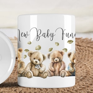May include: White ceramic piggy bank with a slot on top. The front of the bank features a design of four teddy bears sitting in a row with green leaves scattered around them. The text "New Baby Fund" is written above the bears.