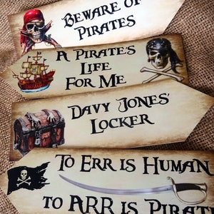 May include: Four wooden signs with pirate-themed sayings. The signs are decorated with skulls, swords, and treasure chests. The sayings are: "Beware of Pirates", "A Pirate's Life For Me", "Davy Jones' Locker", and "To Err Is Human, To Arr Is Pirate".