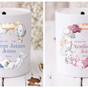 Puede incluir: Dos alcancías de cerámica con un diseño de globo aerostático, estrellas y nubes. La caja azul dice "22 de junio de 2022 3:00 am Oliver James Jones 7lb 12oz". La caja rosa dice "22 de junio de 2022 4:20 pm Amelia Jane Jones 8lb 4oz".