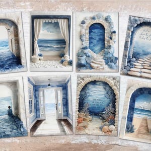 Può includere: Una collezione di stampe artistiche ad acquerello con scene costiere. Ogni stampa raffigura un arco o una finestra che si affaccia sull'oceano, con dettagli come gradini in pietra, tende e scene di spiaggia. La tavolozza dei colori è principalmente blu e bianco.