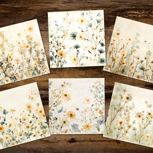 May include: Six square art prints with watercolour floral designs. The prints display arrangements of yellow, blue, and white flowers with green foliage on a cream background. The prints are arranged on a dark wood surface.