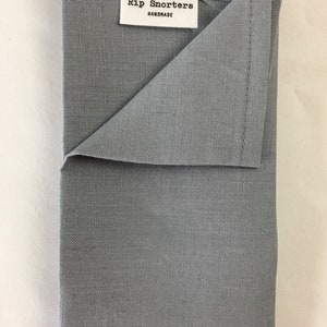 May include: A gray linen tea towel with the text "Rip Snorters Handmade" on a white label.