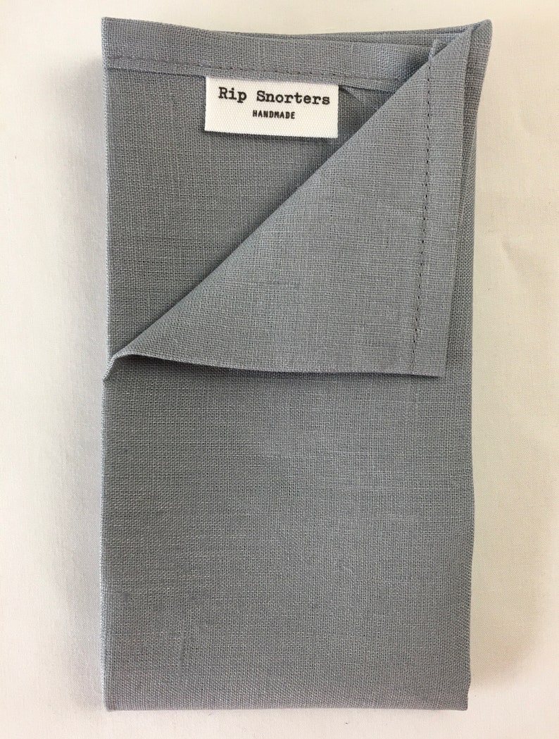 May include: A gray linen tea towel with the text "Rip Snorters Handmade" on a white label.