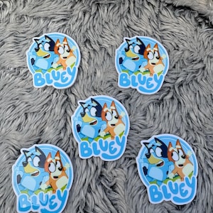 May include: Five stickers featuring Bluey and Bingo from the animated series Bluey. The stickers have a light blue border and the word "BLUEY" in a matching font. The characters are depicted in their signature poses.