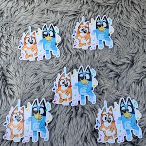 May include: A collection of stickers featuring cartoon dogs, one orange and one blue, dancing with musical notes. The stickers are on a gray, textured surface. The dogs have black eyes and are smiling.