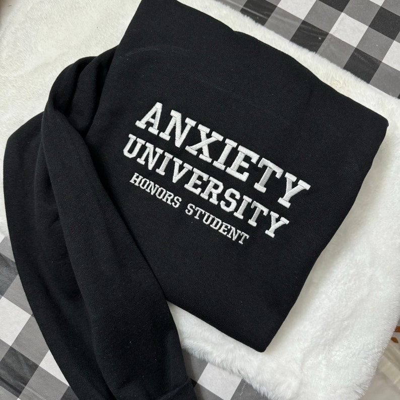 May include: Black sweatshirt with white embroidered text that reads "Anxiety University Honors Student".