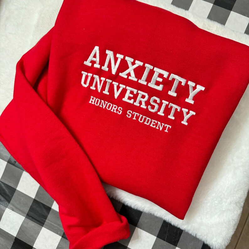 May include: Red sweatshirt with white embroidered text that reads "Anxiety University Honors Student".