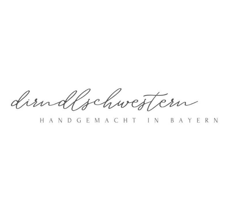 May include: A logo with the cursive text "dirndlschwestern" in a dark gray color. Below the cursive text is the text "HANDGEMACHT IN BAYERN" in a sans-serif font, also in dark gray. The background is white.