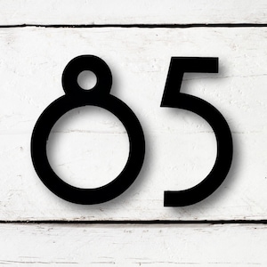 May include: Black metal house numbers with a modern design. The number 8 has a circle in the middle and the number 5 is a simple, bold font.