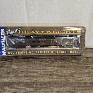 May include: A boxed model train set labeled "Classic Heavyweights" by Walthers. The box features a clear window showcasing a detailed model train car. Text on the box reads "Relive the Golden Age of Train Travel."