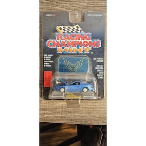 May include: A blue 1996 Pontiac Firebird die-cast model car in its original packaging. The packaging features the Racing Champions Mint logo, issue number 43, and the text "Adult Collectable". The car has its hood open.
