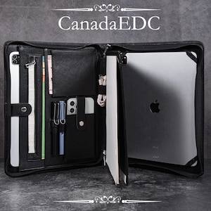 May include: Black leather organizer with multiple compartments, including a tablet sleeve, card slots, and pen holders. The organizer is open, revealing a tablet, notepad, and various accessories. The text "CanadaEDC" is displayed at the top.