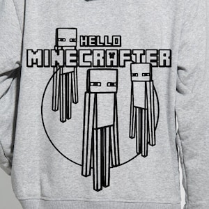 May include: A grey hoodie featuring a black graphic of three Minecraft characters and the text "Hello MINECRAFTER".