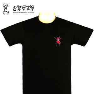 May include: Black t-shirt with a red and blue embroidered spider on the front. The shirt has the text "Arachno Crypt" and "Exotics Embroidery Clothing" on the top.