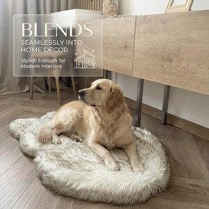 K&ouml;nnte beinhalten: Ein Golden Retriever liegt auf einem Haustierbett aus Kunstfell. Das Bett ist oval und hat eine Mischung aus wei&szlig;en und grauen T&ouml;nen. Das Bild enth&auml;lt Text, der lautet: "BLENDS SEAMLESSLY INTO HOME DECOR" und "Stylish Enough for Modern Interiors."