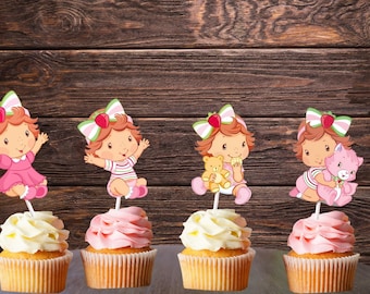 May include: Four cupcakes with toppers featuring a cartoon girl with red hair, a bow, and a dress or striped outfit. The cupcakes have white or pink frosting and are in yellow cupcake liners. The background is a dark wood.