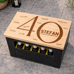Könnte beinhalten: Eine schwarze Holzkiste mit einem hellen Holzdeckel. Der Deckel ist mit der Zahl 40, Namen und dem Namen "STEFAN" mit dem Text "ALLES GUTE ZUM GEBURTSTAG!" graviert. Die Kiste enthält Flaschen.