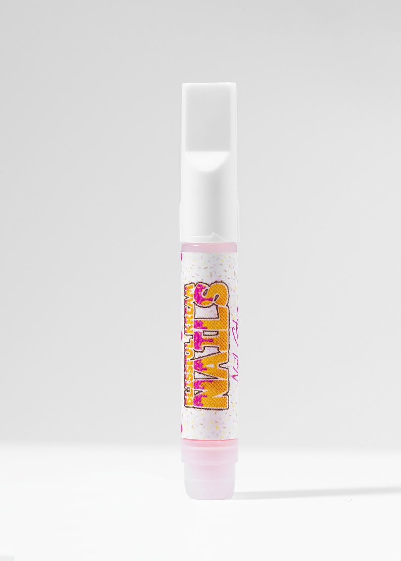 May include: A white tube with a pink cap and a label that says "WAFFLES" with the words "DISGUISED AS CREAM" in smaller font underneath. The label has a pink and yellow design.