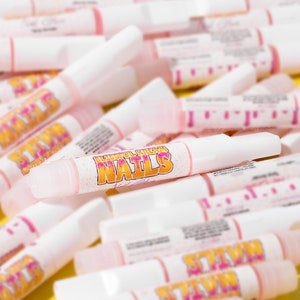 May include: A close-up of several small white bottles with pink and yellow labels. The bottles are labelled "Blissful Kream Nails".