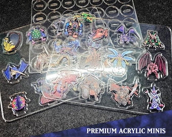 Puede incluir: Un conjunto de mini figuras de acrílico premium con diseños de monstruos variados. Las figuras están dispuestas sobre láminas de plástico transparente con recortes individuales. El texto "PREMIUM ACRYLIC MINIS" y "MONSTER PACK 11" es visible.
