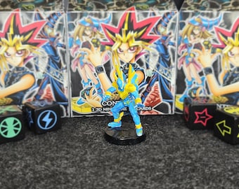 Könnte beinhalten: Eine blau-gelbe Figur eines Yu-Gi-Oh!-Charakters auf einem schwarzen Sockel. Im Hintergrund befinden sich Kartons mit Charakterillustrationen und Würfel mit Symbolen. Der Text "1 3D MIN" ist sichtbar.