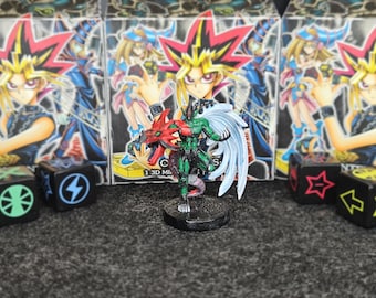 Könnte beinhalten: Eine grün-rote Monsterfigur mit weißen Flügeln, auf einem schwarzen Sockel. Dahinter befinden sich drei Boxen mit Anime-Charakteren. Würfel mit Symbolen befinden sich vor den Boxen.