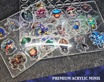 Pode incluir: Um conjunto de 10 miniaturas de acrílico que representam várias criaturas fantásticas, incluindo um goblin, um dragão, um mago e uma fada. As miniaturas são exibidas em uma base de acrílico transparente com uma etiqueta "Monster Pack 10" e o texto "Premium Acrylic Minis".