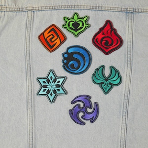 Puede incluir: Siete parches bordados en varios colores y dise&ntilde;os, incluyendo un copo de nieve, un coraz&oacute;n, una llama, un remolino, un p&aacute;jaro y dos dise&ntilde;os abstractos, est&aacute;n cosidos en una chaqueta vaquera azul claro.