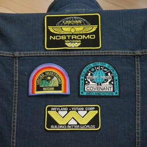 May include: A blue denim jacket with four embroidered patches. The patches are for the "Nostromo" and "Covenant" spaceships from the Alien franchise. The patches feature the text "USCSS Nostromo 180286", "Building Better Worlds", "Covenant", and "Weyland-Yutani".