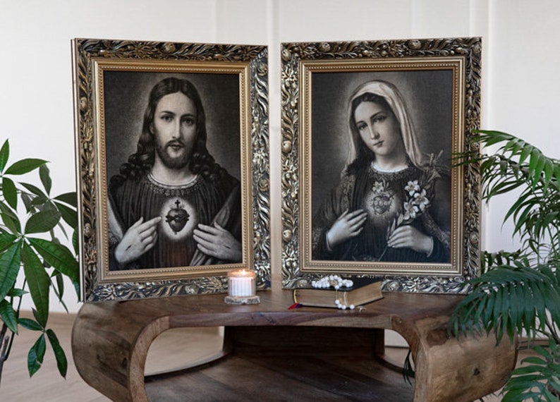 May include: Two framed black and white religious images with gold frames. The image on the left depicts Jesus with his heart exposed, and the image on the right depicts Mary with her heart exposed.