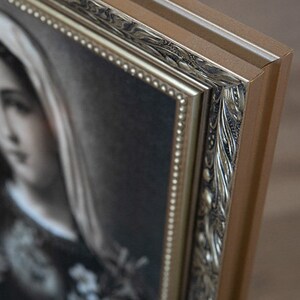May include: A framed black and white portrait of a woman wearing a veil. The frame is ornate with gold accents and a beaded border.