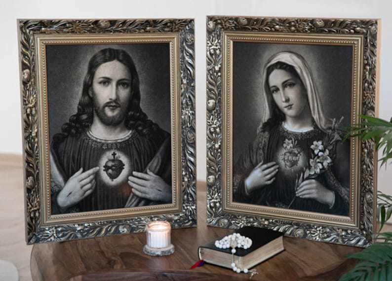 May include: Two framed religious images, one depicting Jesus with his heart exposed and the other depicting Mary with her heart exposed. Both images are in black and white and have a gold frame.