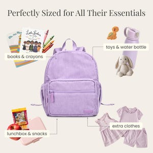 K&ouml;nnte beinhalten: Ein lavendelfarbener Cord-Rucksack mit einer Vordertasche, umgeben von Schulmaterial, Snacks, einer Wasserflasche, Spielzeug und zus&auml;tzlicher Kleidung. Der Text lautet "Perfectly Sized for All Their Essentials."