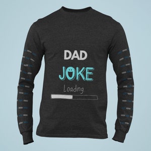 May include: A dark grey long-sleeved shirt with a white and blue design. The shirt says "DAD JOKE Loading" with a progress bar.