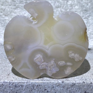 May include: White agate carving shaped like an apple with a swirl pattern and white and light brown inclusions.