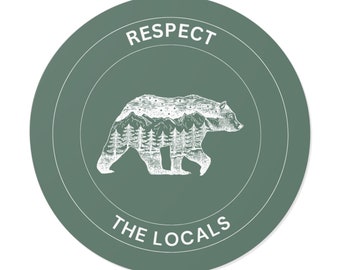 May include: A green circle sticker with a white outline. The sticker features a white bear with a mountain range inside its body. The text "RESPECT THE LOCALS" is written below the bear.