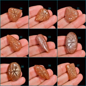 Peut inclure: Neuf cabochons de pierre de soleil avec des motifs grav&eacute;s, num&eacute;rot&eacute;s de 29 &agrave; 37. Les pierres sont de couleur orange clair avec une finition chatoyante et scintillante.