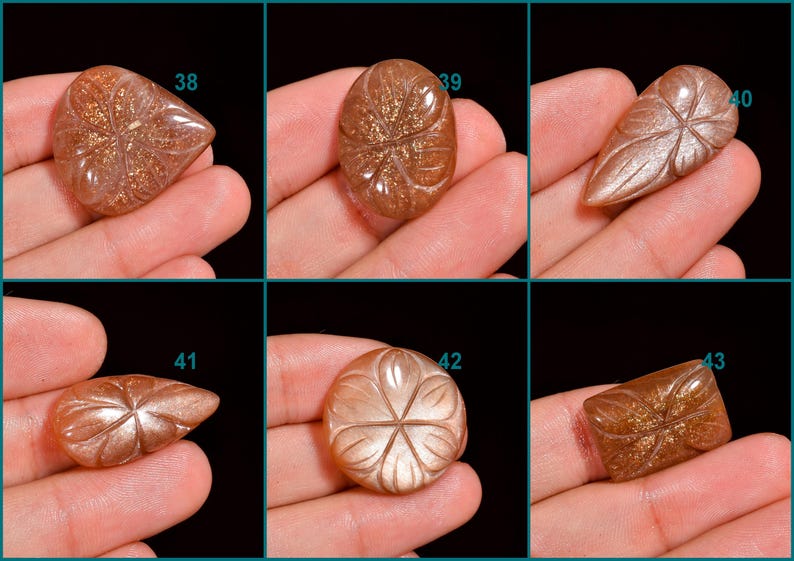 Peut inclure: Six cabochons de pierre de soleil avec des motifs floraux grav&eacute;s. Les pierres sont de diff&eacute;rentes nuances de brun et d'orange avec un effet chatoyant et iris&eacute;. Les cabochons sont num&eacute;rot&eacute;s de 38 &agrave; 43.
