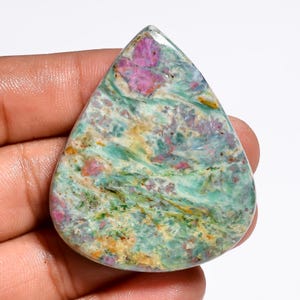 Puede incluir: Una piedra preciosa pulida en forma de lágrima con un patrón jaspeado de remolinos en verde azulado, verde claro y blanco, acentuado con parches distintos de inclusiones en magenta intenso y rosa en toda la superficie lisa y brillante.