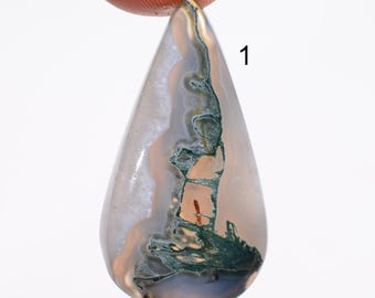 May include: A teardrop-shaped gemstone with a mix of colors. The stone features areas of white, gray, tan, and dark green. The number "1" is printed on the right side of the stone.