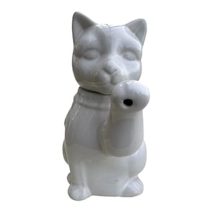 Può includere: Teiera in ceramica bianca a forma di gatto con un beccuccio a forma di zampa di gatto. La teiera ha una finitura liscia e lucida.