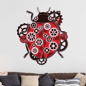 Puede incluir: Una mariquita roja y negra con engranajes y ruedas dentadas intrincados, una decoración de pared de estilo steampunk, colgada en una pared blanca sobre un sofá marrón con almohadas.