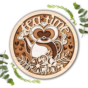 Puede incluir: Un letrero redondo de madera con el texto "tea time" en una fuente decorativa. El letrero presenta una ilustración estilizada de una tetera con corazones y flores.