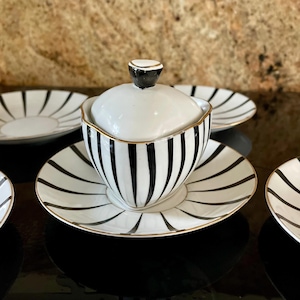 May include: A black and white striped porcelain creamer and sugar set with gold trim. The set includes a creamer with a lid and a saucer. The creamer and saucer have a black and white striped design with gold trim.