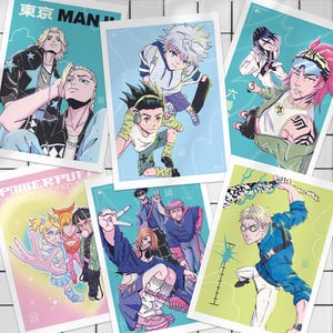 Op de afbeelding: Een verzameling kunstprints in anime-stijl met verschillende personages in dynamische poses. De prints tonen een reeks levendige kleuren en gedetailleerde illustraties, met tekstelementen zoals "Tokyo Man" en "Powerpuff".