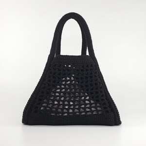 Op de afbeelding: Een zwarte gehaakte tote bag met een driehoekige vorm en twee handvatten.