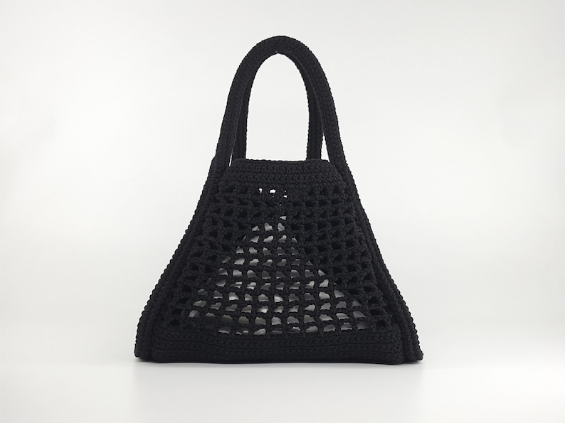 Op de afbeelding: Een zwarte gehaakte tote bag met een driehoekige vorm en twee handvatten.