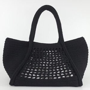 Op de afbeelding: Zwarte gehaakte tote bag met een gaasontwerp. De tas heeft twee handvatten.