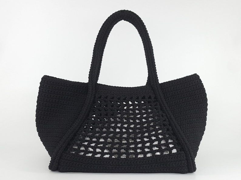 Op de afbeelding: Zwarte gehaakte tote bag met een gaasontwerp. De tas heeft twee handvatten.